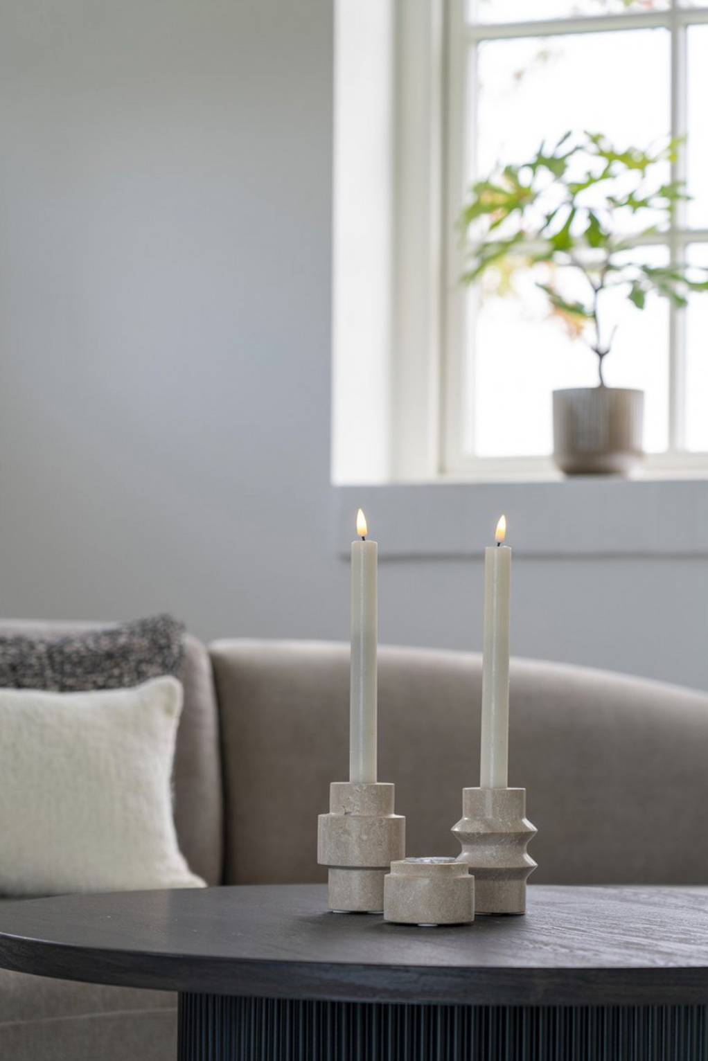 Lichte sculpturale kandelaars met geometrische vormen op een salontafel